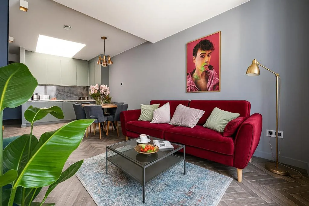Salon apartamentu Red z czerwoną sofą i oknami na kamienice